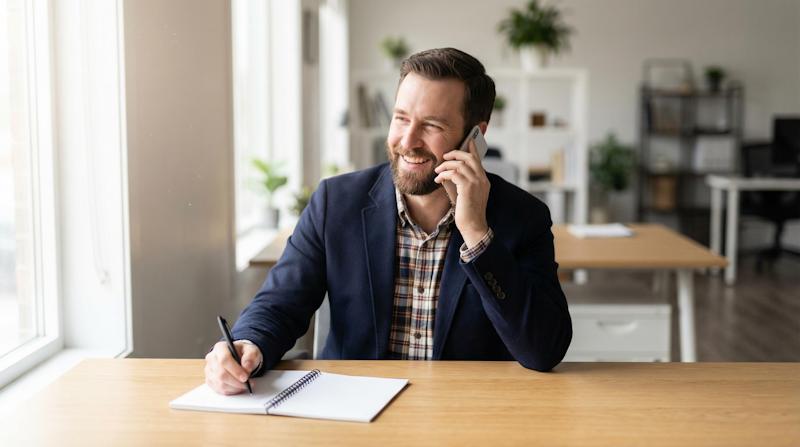 Freundlicher Umzugshelfer nimmt Kundenanfrage am Telefon entgegen – Umzugflex24