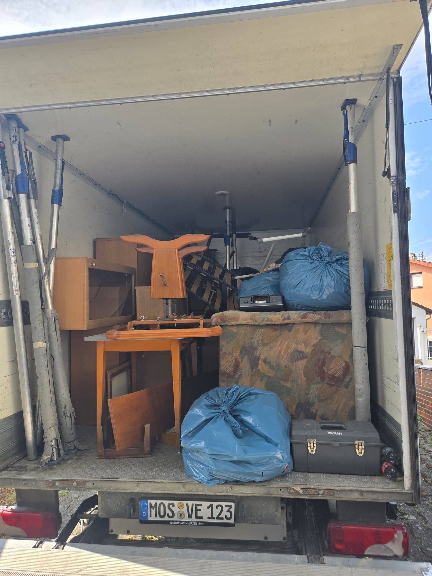 Beladener Kofferwagen mit Möbeln und Säcken während der Entrümpelung