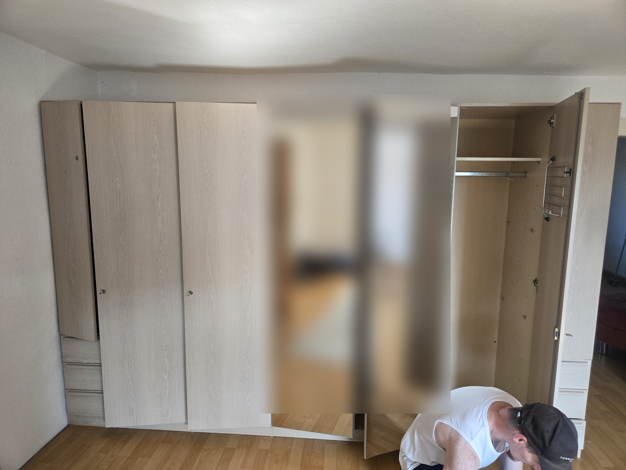Monteur demontiert einen großen Kleiderschrank mit Spiegeltüren im Schlafzimmer