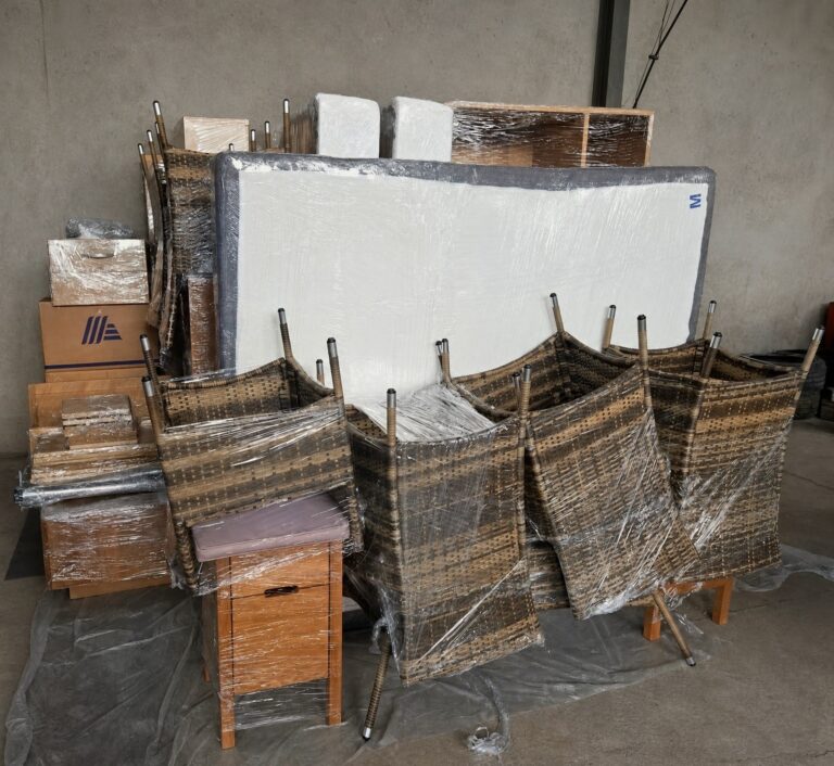 Möbeleinlagerung im Überblick: Boxspringbett, Rattanstühle, Kartons und Schrankteile einzeln verpackt