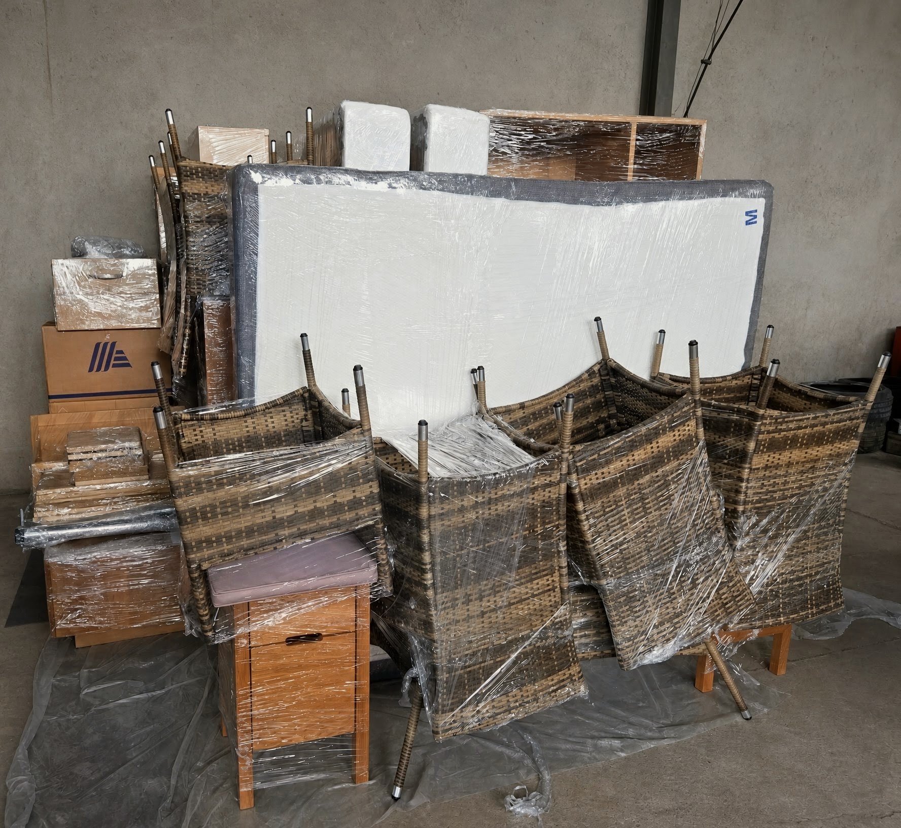 Möbeleinlagerung im Überblick: Boxspringbett, Rattanstühle, Kartons und Schrankteile einzeln verpackt